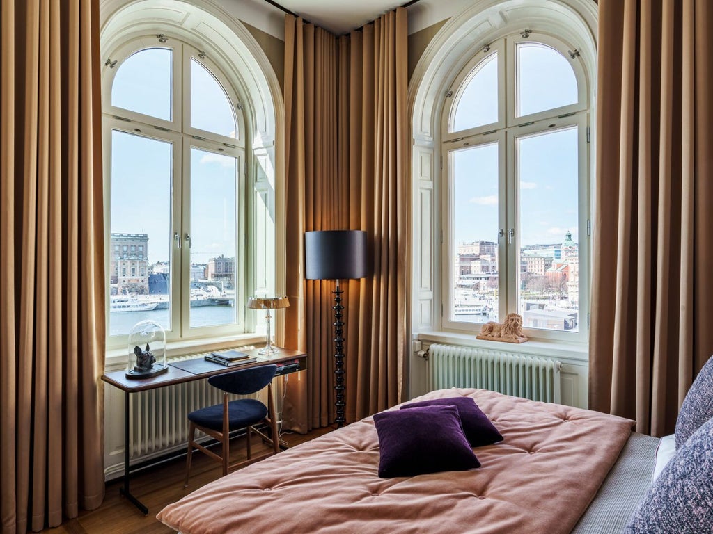 Luxurious spacious hotel room with plush king bed, soft neutral tones, elegant modern Swedish design, large windows with city or harbor view