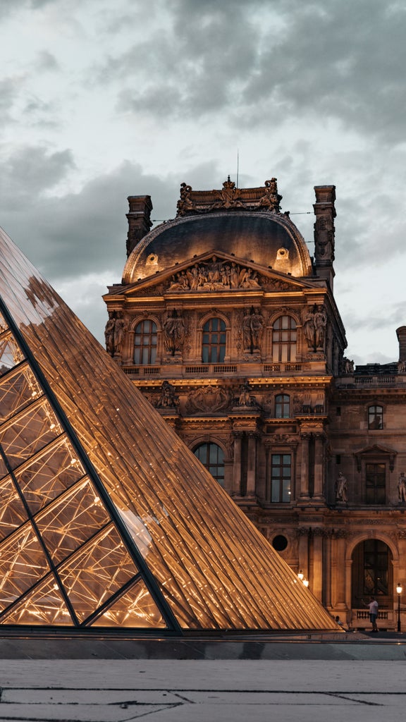 Historic Eiffel Tower soaring above elegant Haussmanian buildings at sunset, with golden light illuminating romantic Parisian streets