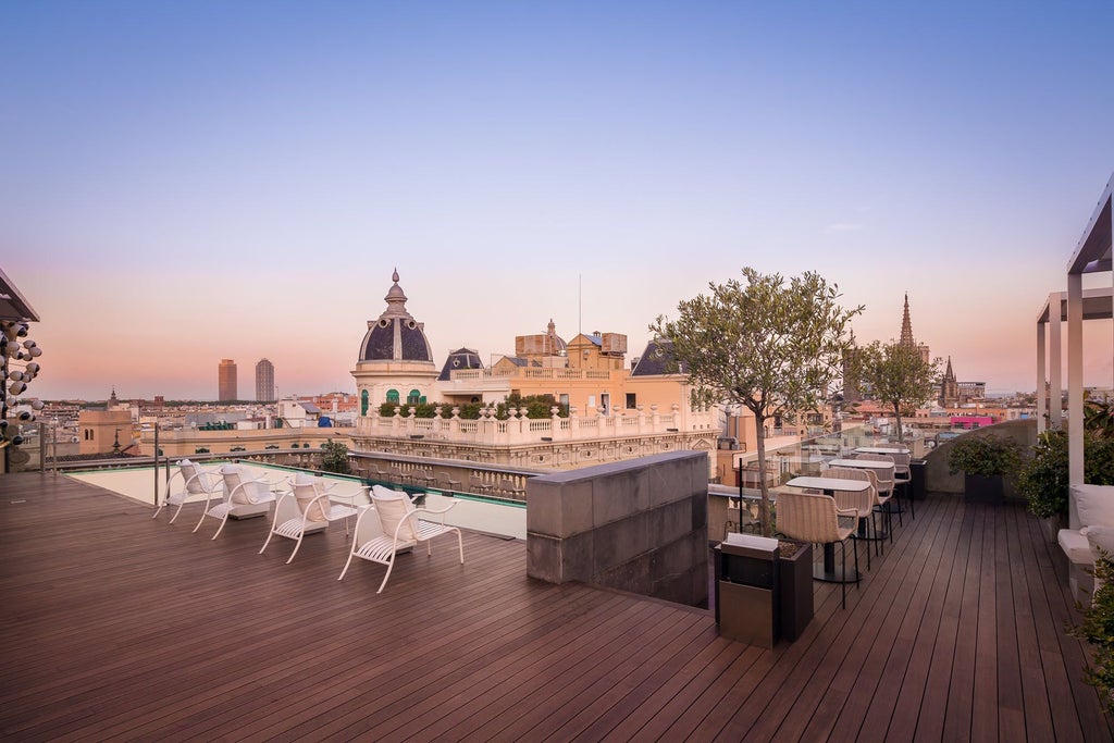 Sleek rooftop terrace with contemporary design overlooking Barcelona skyline, featuring geometric pool and chic lounge area at luxury boutique hotel