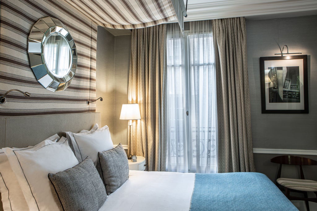 Elegant Parisian hotel room with soft neutral tones, plush white bedding, refined classic furnishings, and soft natural light streaming through sheer curtains