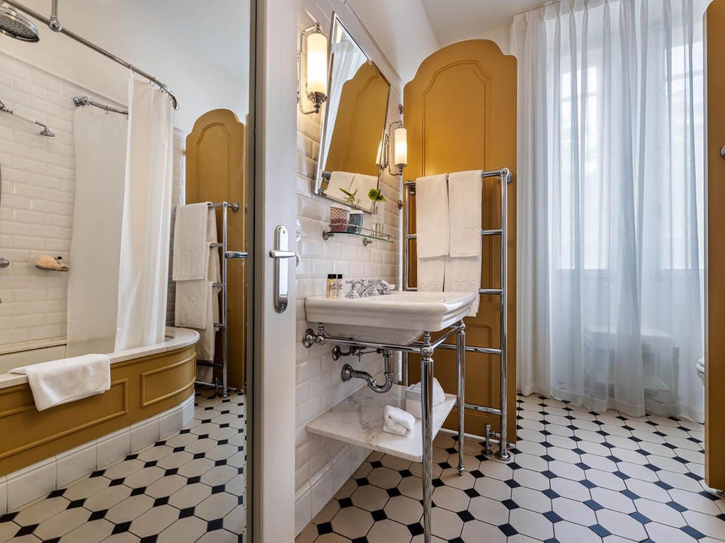 Elegant white-walled hotel room with plush king bed, ornate traditional Portuguese furnishings, crystal chandelier, and large windows overlooking lush gardens