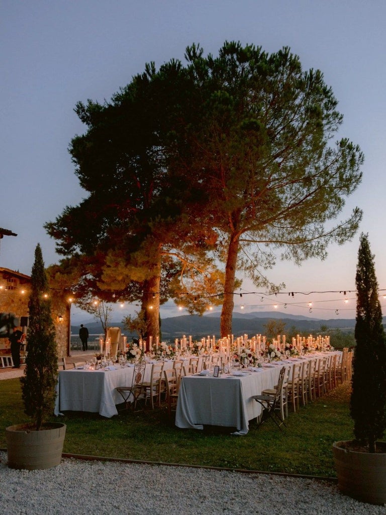 Luxurious Tuscan wine resort with elegant stone buildings, rolling vineyards, and golden sunset light casting warmth over the picturesque landscape