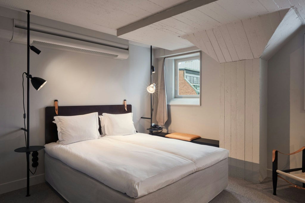 Modern minimalist Scandinavian hotel room with sleek queen bed, neutral color palette, and contemporary Nordic design elements at Blique by Scenset in Sweden