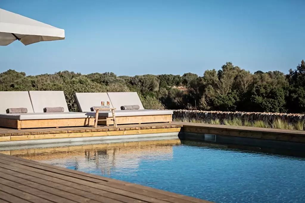 Elegant stone tower hotel with terracotta roof, nestled in Spanish landscape, featuring sun-drenched stone walls and lush Mediterranean vegetation