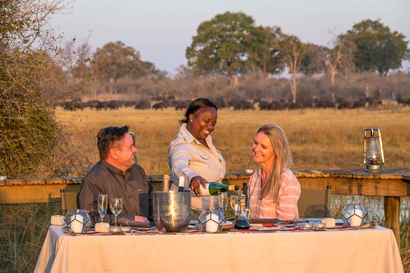 Elevated safari lodge overlooking African plains with luxurious tented suite, private deck and wooden walkways amid acacia trees