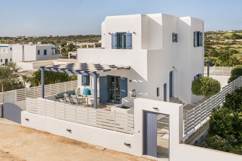 Modern Mediterranean stone villa with terracotta roof, nestled among olive trees overlooking azure Aegean Sea, showcasing elegant architectural design and serene landscape