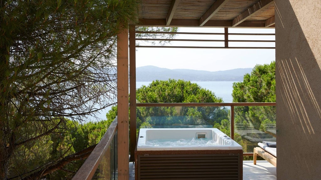 Luxurious premium suite with private hot tub overlooking azure Aegean waters, featuring elegant white decor and expansive Greek island scenery at sunset