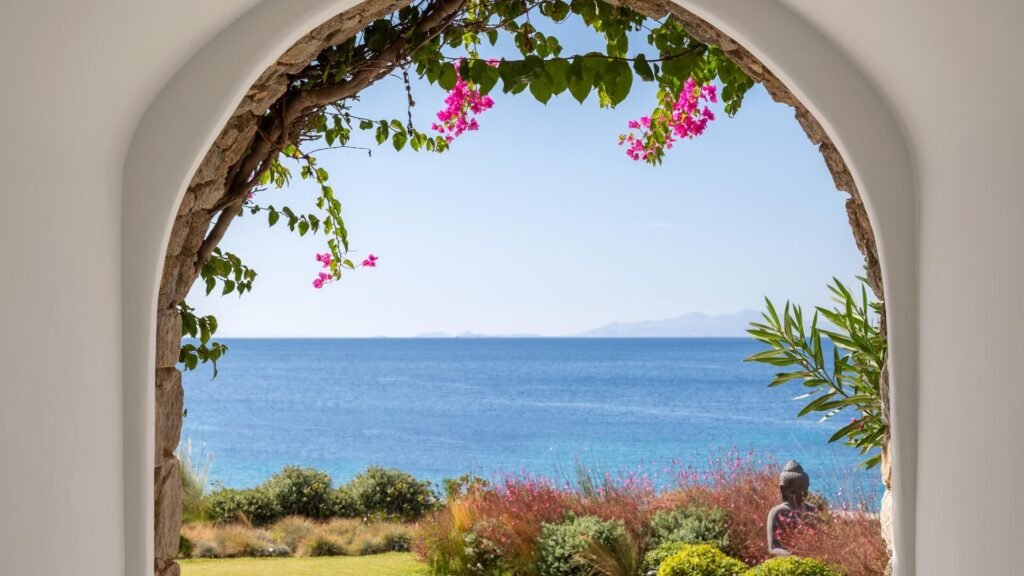 Elegant infinity pool overlooking the Aegean Sea at sunset, with white cubist architecture and plush loungers on stone terraces