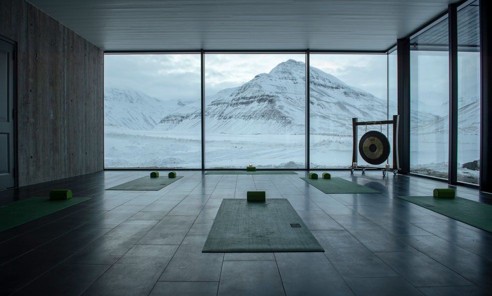 Contemporary Nordic lodge with floor-to-ceiling windows nestled in snowy Icelandic mountains, reflecting in a geothermal infinity pool