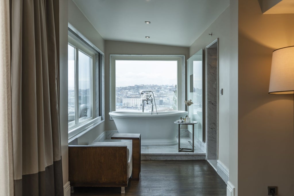 Luxurious penthouse suite with panoramic city views, plush king bed, marble bathroom, and elegant modern decor in historic Istanbul hotel