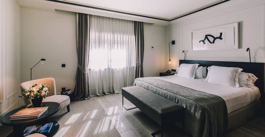 Elegant deluxe hotel room with minimalist design, warm wood tones, modern lighting, and sophisticated decor at Sant Francesc Hotel Singular in Spain