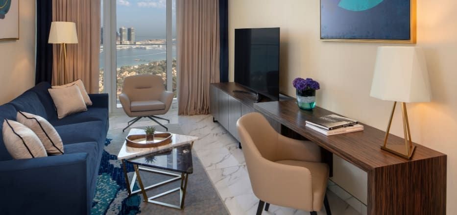 Spacious one-bedroom apartment with modern furnishings, Dubai skyline view, luxurious king bed, sleek living area, and contemporary bathroom in Scenset hotel suite