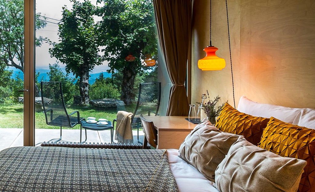 Elegant mountain-view double room with private balcony, featuring warm wood tones, minimalist design, and panoramic scenery at Casa das Penhas Douradas.