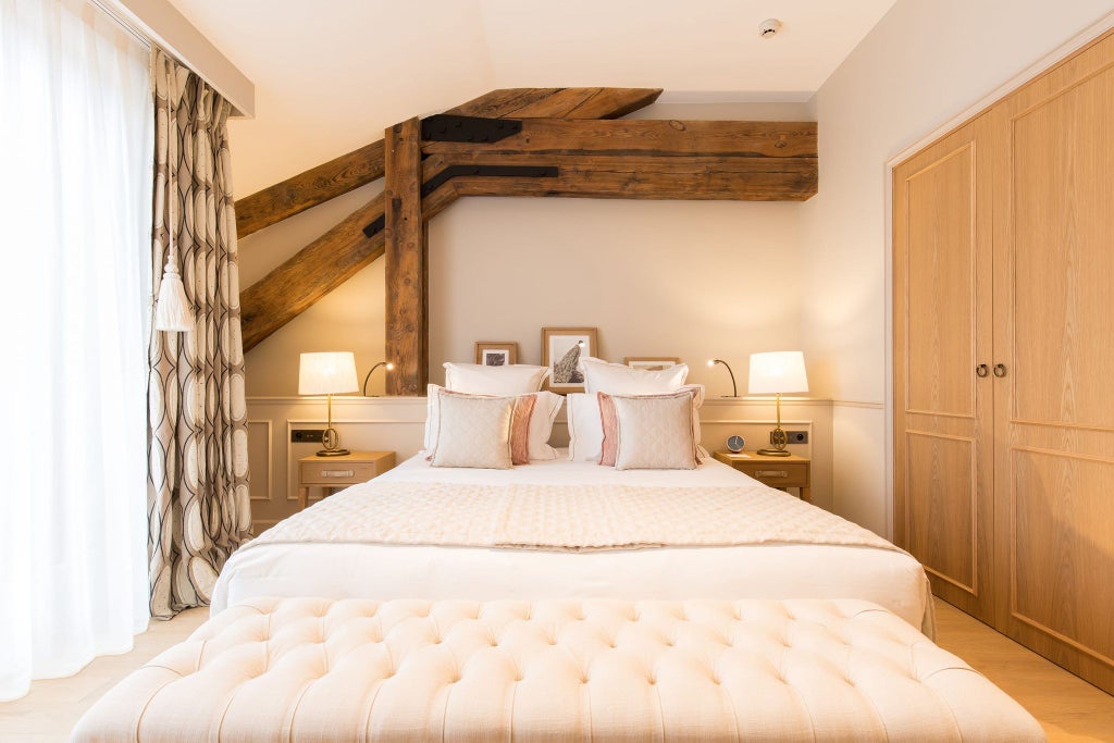 Elegant premier hotel room with plush white bedding, soft neutral tones, large window, and sophisticated French design at Chais Monnet Spa in Cognac