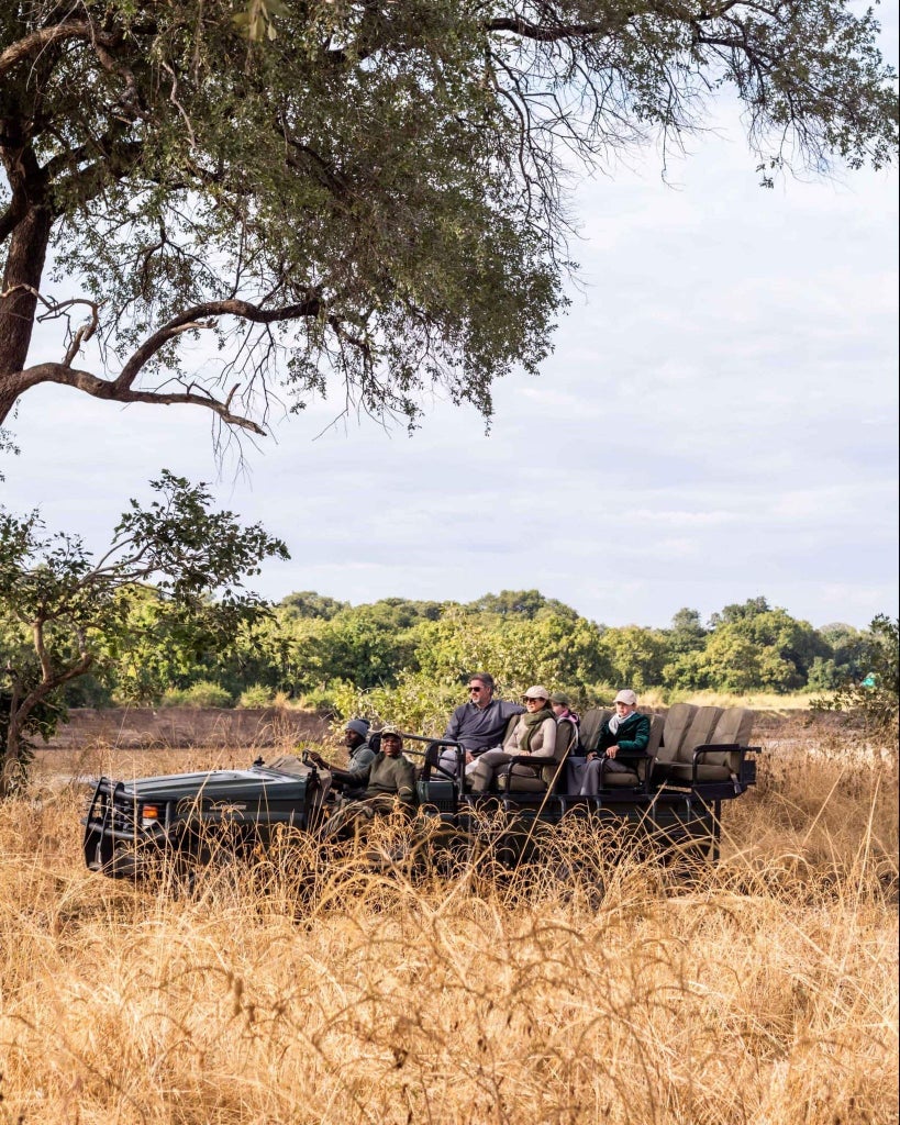 Luxury safari tent nestled in lush Lower Zambezi wilderness, with canvas walls, wooden deck, and panoramic views of pristine African riverine landscape