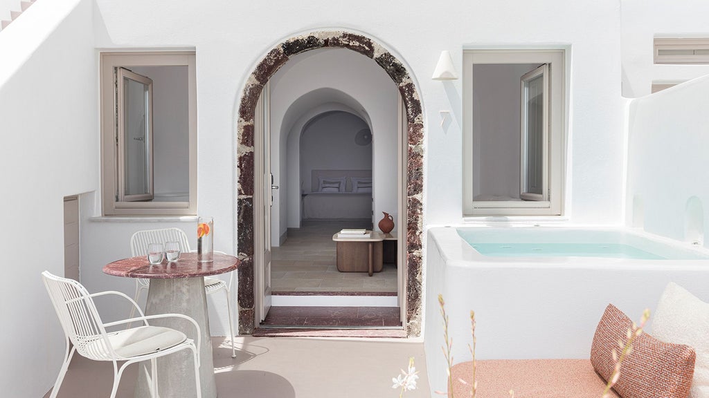 Luxurious white-washed Superior Suite at Canaves Ena in Santorini, featuring minimalist design, private terrace with Aegean Sea panorama, and elegant modern furnishings.