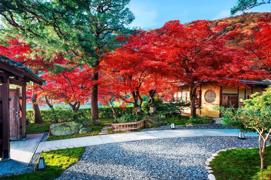 Traditional Japanese ryokan with wooden exterior overlooking serene garden, featuring a stone lantern and manicured bonsai trees at dusk