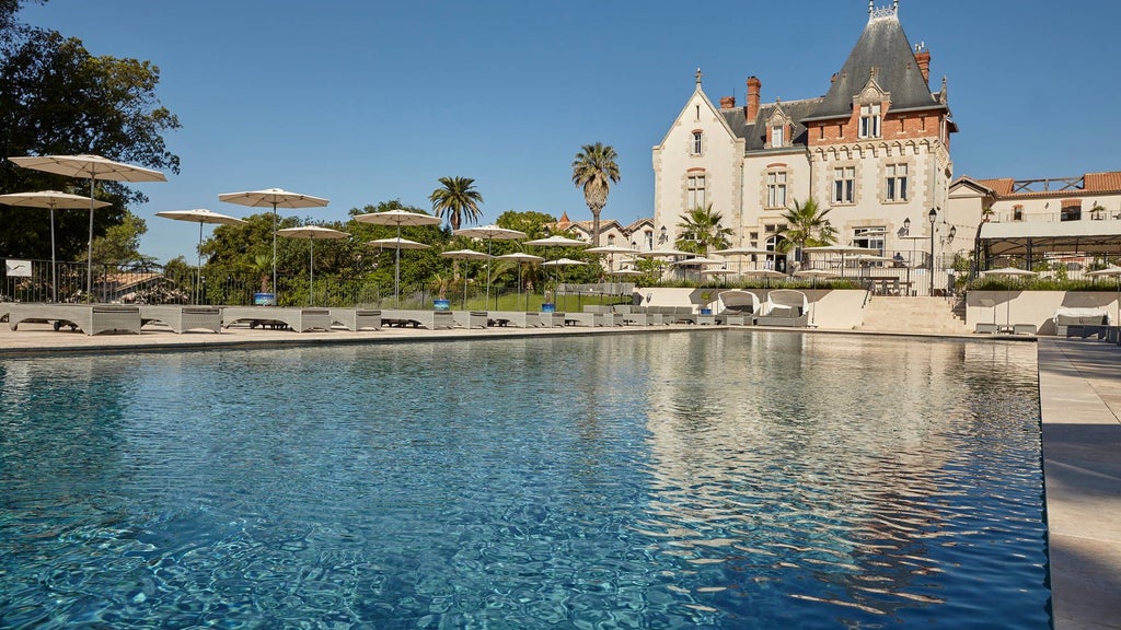 Luxurious French château hotel nestled among rolling vineyards, with elegant stone facade, manicured gardens, and golden sunset light casting warmth across landscape