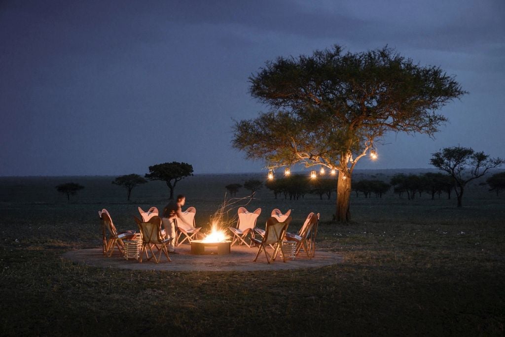 Luxurious canvas safari tent with elegant wooden deck overlooking the Serengeti plains, golden grasslands stretching to the horizon