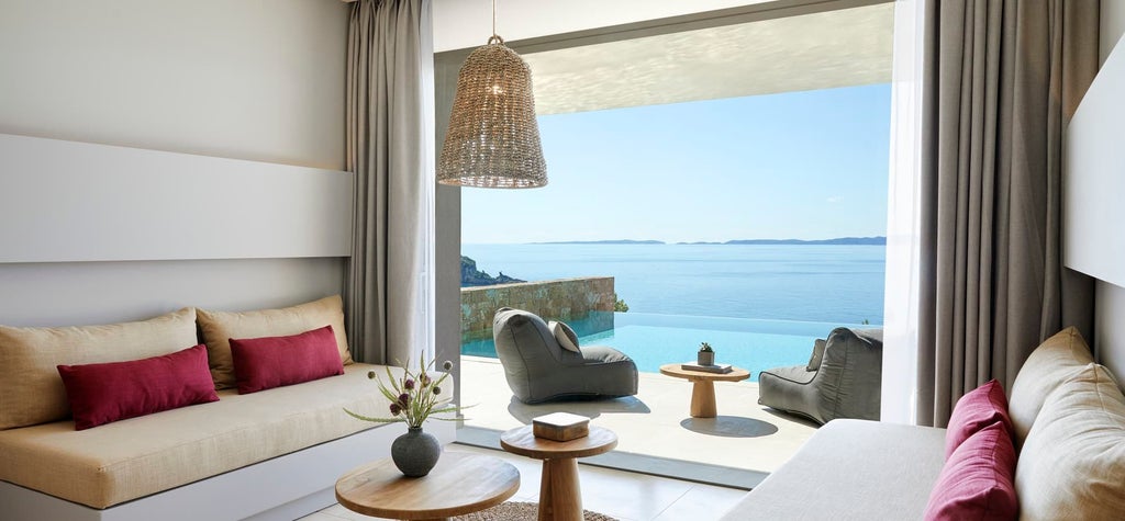 Elegant Deluxe Double Room with panoramic azure Aegean Sea view, featuring modern minimalist design and luxurious white linens in a Greek coastal hotel