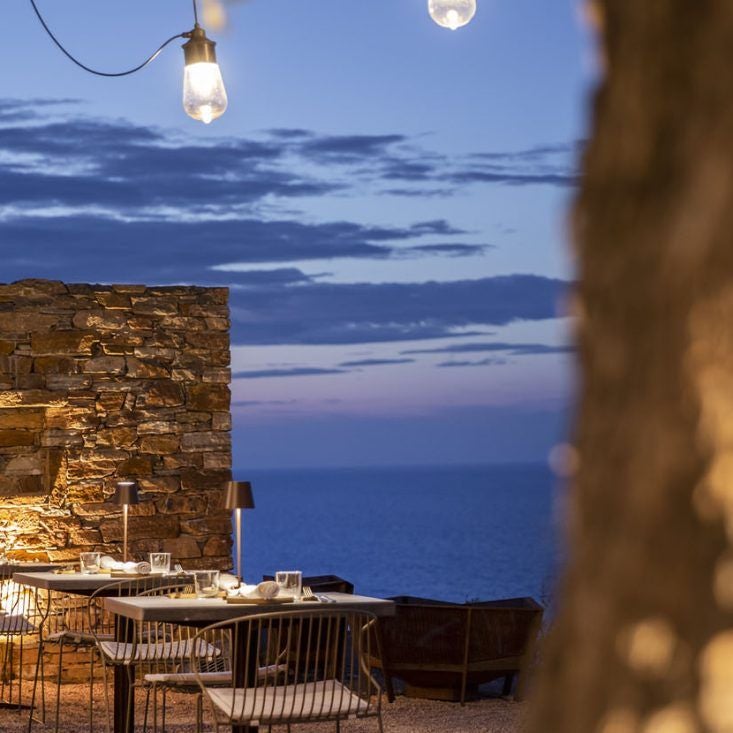 Minimalist white luxury hotel with curved architecture overlooking azure Aegean Sea, Sifnos island sunset, sleek infinity pool and stark Mediterranean landscape