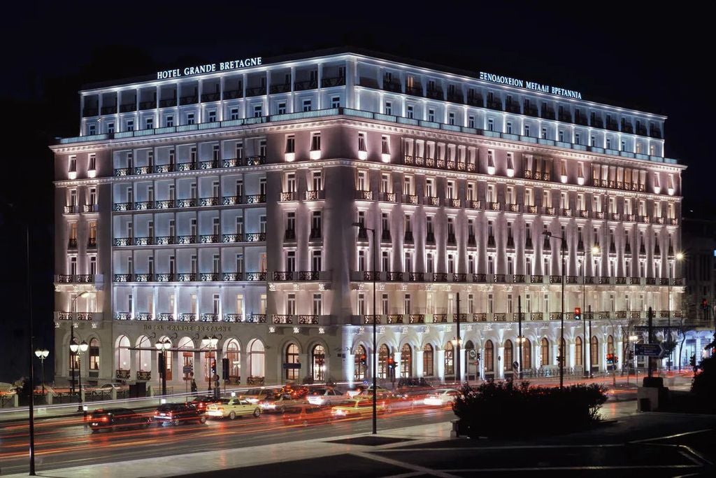 Opulent facade of Hotel Grande Bretagne in Athens with neoclassical architecture, ornate balconies, and warm lighting at dusk