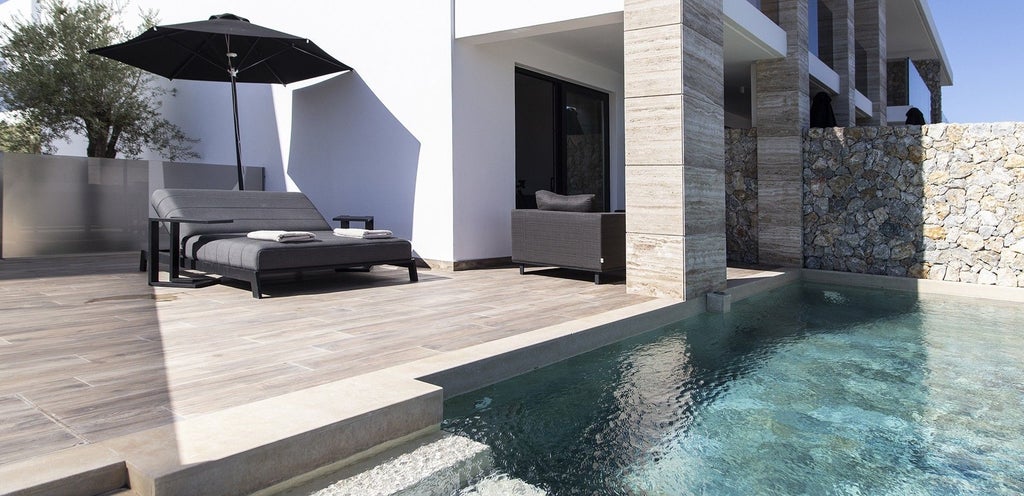 Modern Greek design suite with sleek white minimalist interior, private plunge pool, and expansive sea view overlooking scenic coastal landscape at dusk