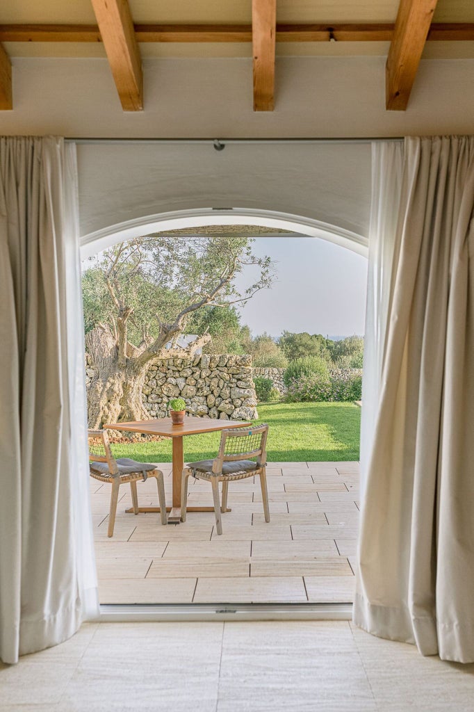 Rustic-chic cottage interior with whitewashed walls, minimalist wooden furniture, and warm natural light in a serene Spanish countryside setting