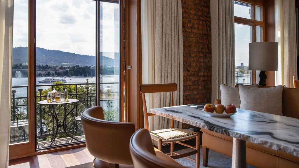 Luxurious Swiss lakeside hotel with elegant white facade, floor-to-ceiling windows overlooking Lake Zurich's sparkling waters and urban landscape