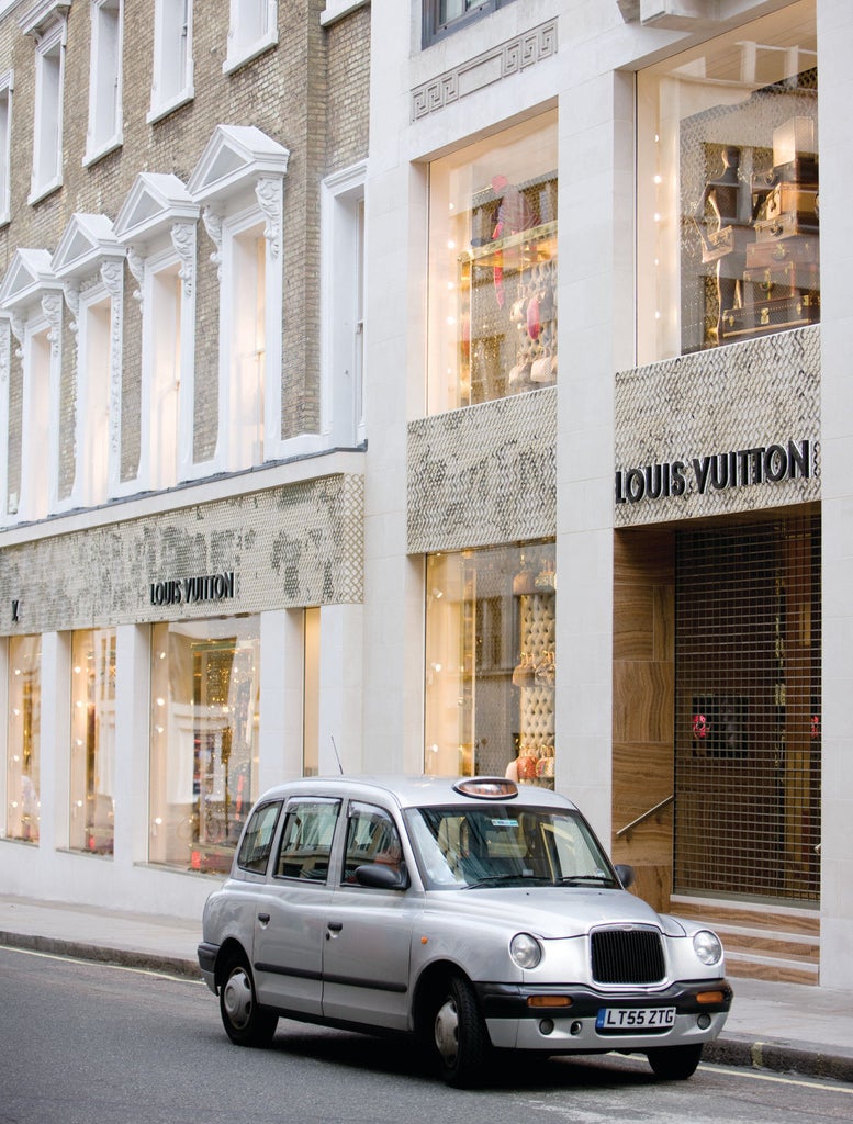 Elegant facade of luxury hotel with illuminated entrance, classic limestone architecture, and manicured gardens in central London