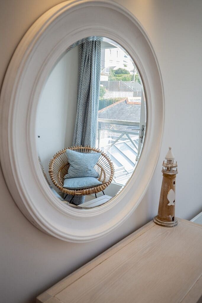 Elegant seaside hotel room with coastal charm, featuring crisp white linens, nautical accents, and a picturesque view of the scenset village of St Mawes, Cornwall.