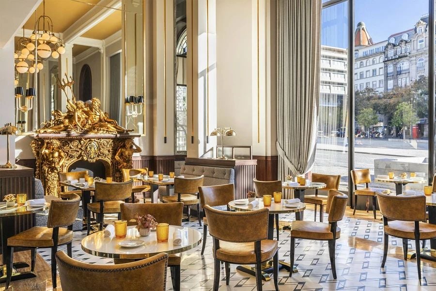 Elegant Art Nouveau facade of luxurious hotel in Porto, Portugal, with ornate golden details and classic architectural grandeur illuminated at dusk