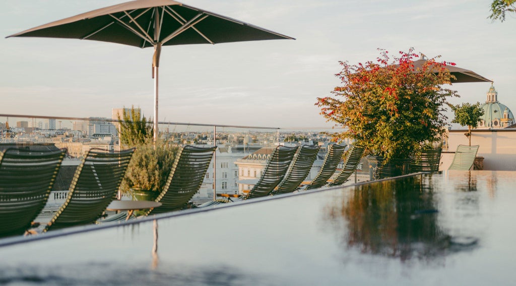 Elegant Viennese hotel with grand white facade, ornate balconies, and classic Austrian architectural details against a blue sky backdrop