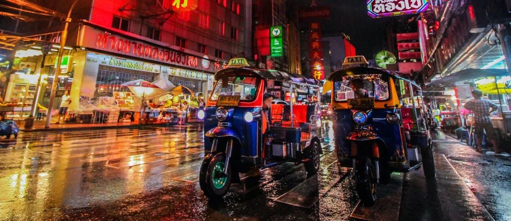 Luxury tuk tuk food tour through vibrant Bangkok street market, featuring colorful street food stalls, gleaming metallic food carts, and local culinary delights at sunset