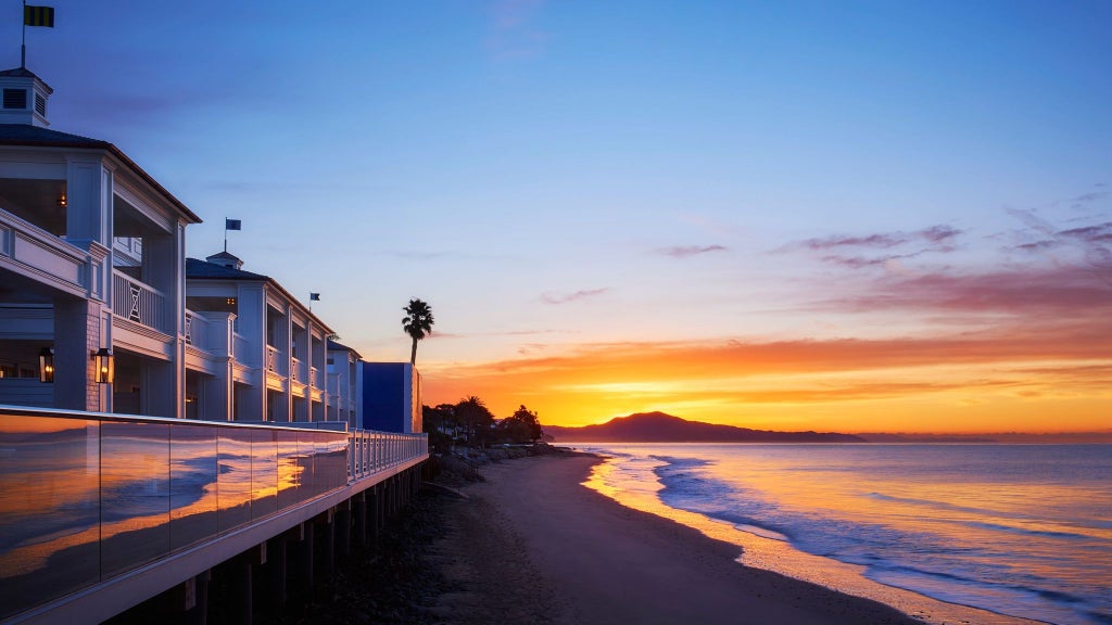 Luxurious coastal resort with white buildings, lush green landscaping, and pristine blue ocean views at a beachfront property in California