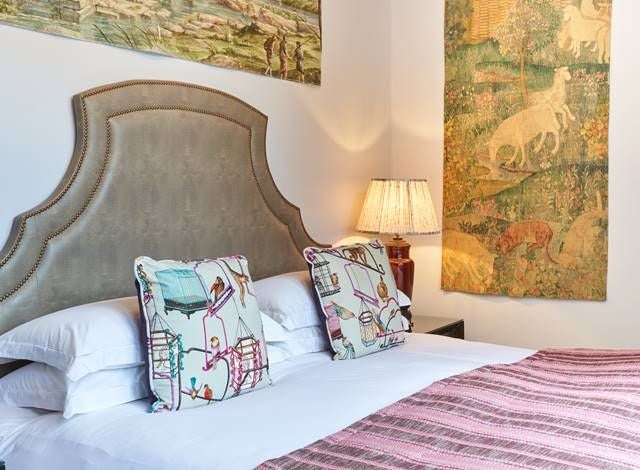 Cozy boutique double room with minimalist design, soft blue-gray color palette, plush bedding, and artful bird-themed decor in a charming UK hotel.