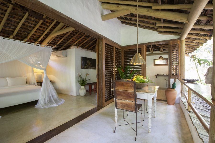 Luxurious rustic Brazilian villa suite with wooden furnishings, tropical greenery, and a private outdoor terrace at UXUA Casa Hotel and Spa in Trancoso