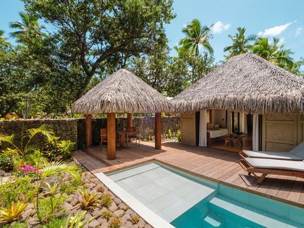 Luxurious overwater villa with private infinity pool, wooden deck, and direct lagoon access, surrounded by turquoise Polynesian waters