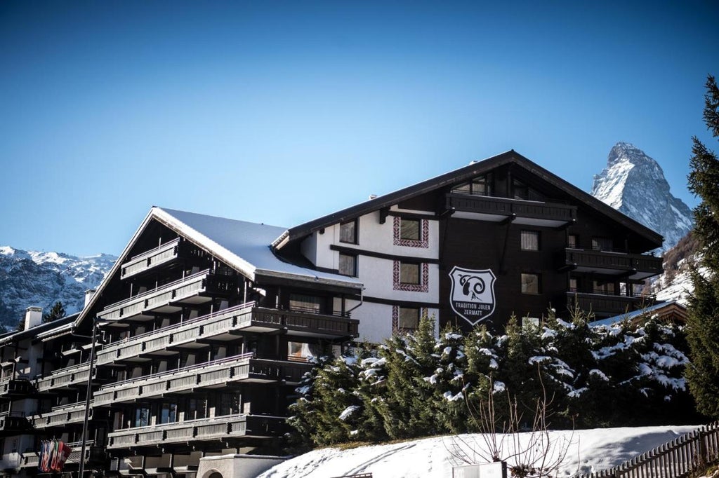 Luxurious Swiss alpine hotel nestled in snowy mountains, featuring wooden chalet architecture with balconies and warm glowing windows