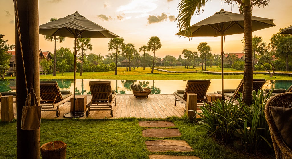 Serene Cambodian luxury resort with traditional wooden villas and lush rice paddies, reflecting authentic local architecture at sunset