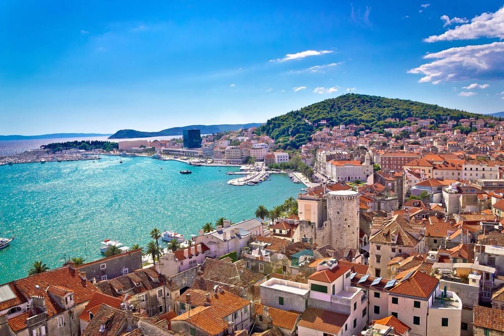 Aerial view of Split, Croatia showcasing historic old town with terracotta rooftops, limestone buildings, and azure Adriatic Sea coastline