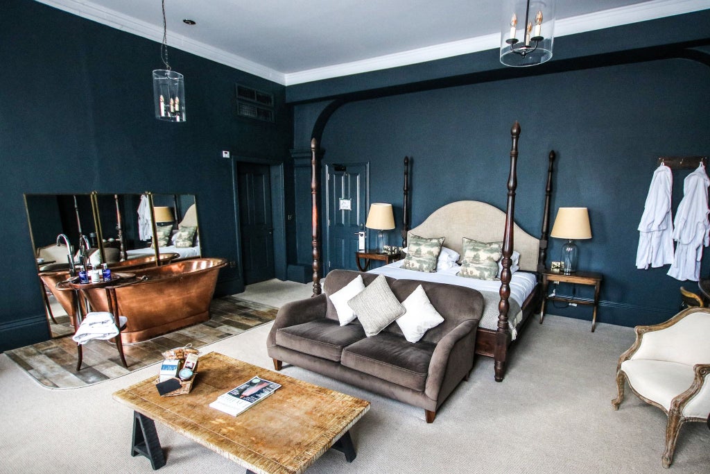 Luxurious hotel room with plush king-sized bed, elegant wooden furnishings, soft ambient lighting, and rich textured decor at Kings Head Hotel in the United Kingdom.