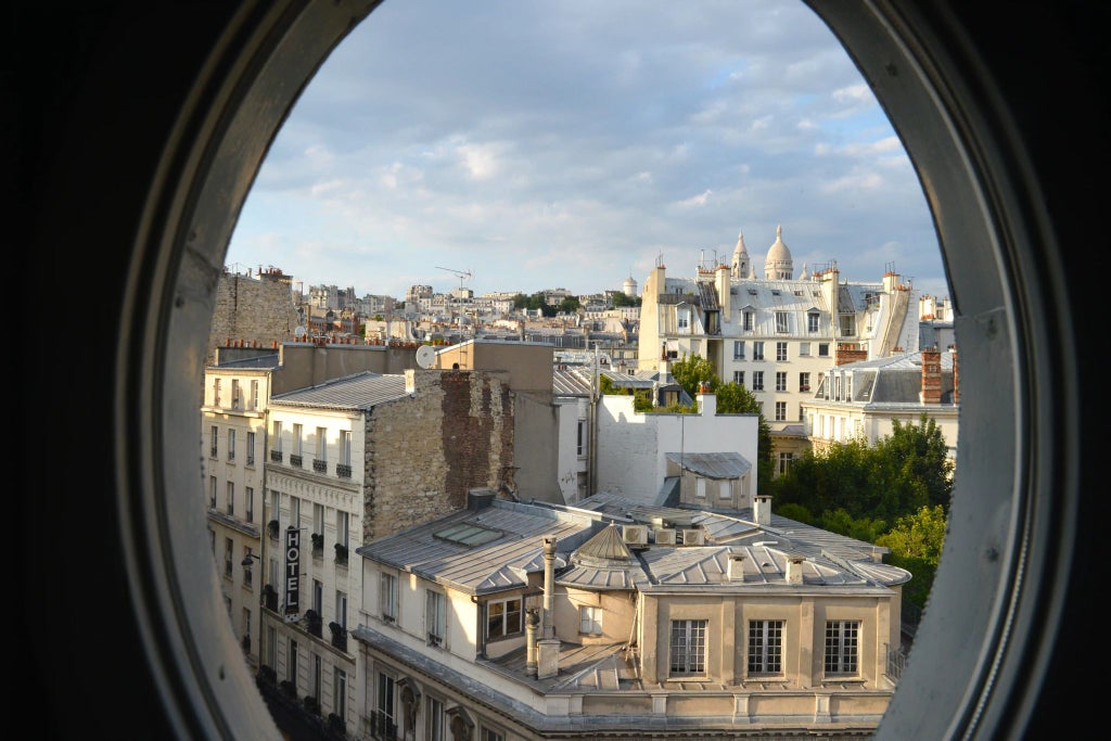 Elegant Parisian hotel room with plush burgundy headboard, vintage-inspired decor, and soft ambient lighting in the Grand Pigalle Hotel's signature room