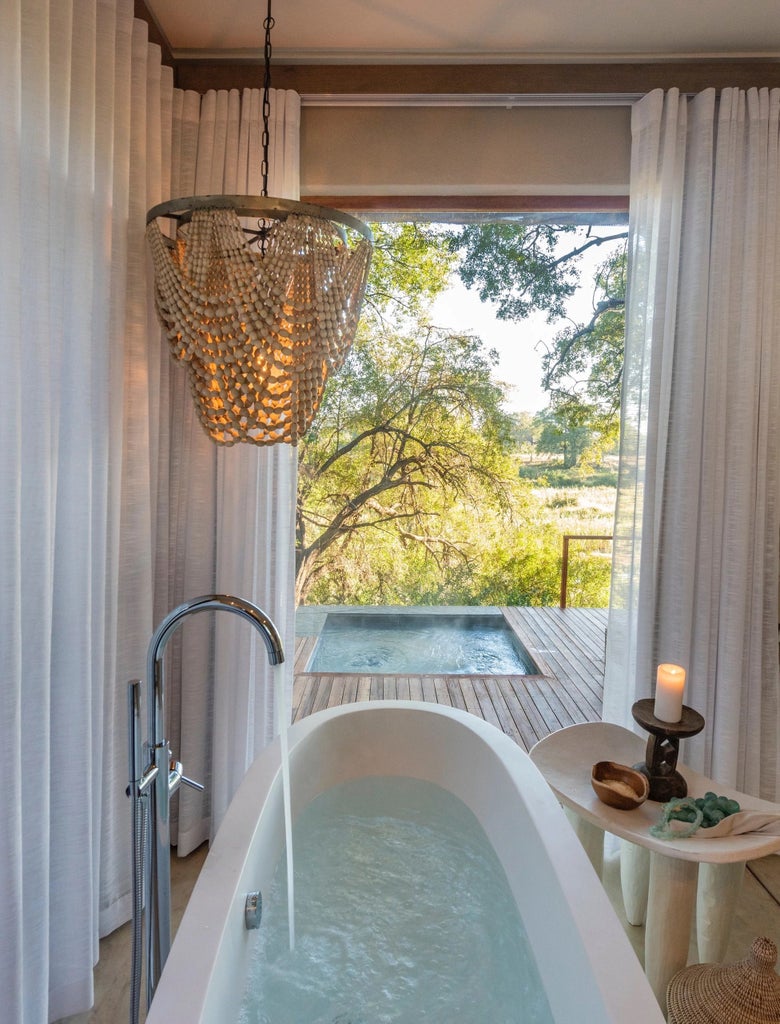 Elegant suite at Dulini River Lodge overlooking Sabi Sands, featuring canvas walls, thatched roof, and private viewing deck with bushveld vista