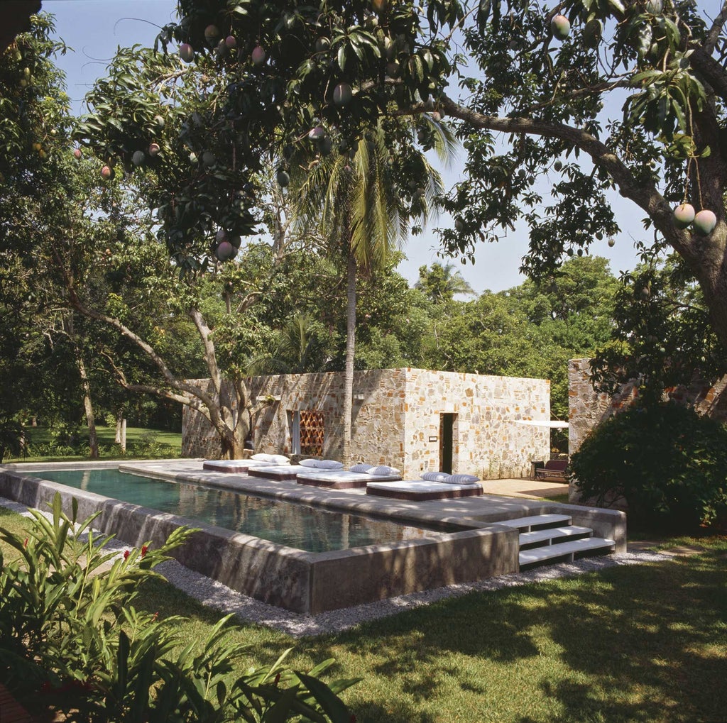 Elegant colonial-style villa with lush tropical gardens, pristine white facade, and vibrant turquoise pool nestled in a serene Mexican landscape