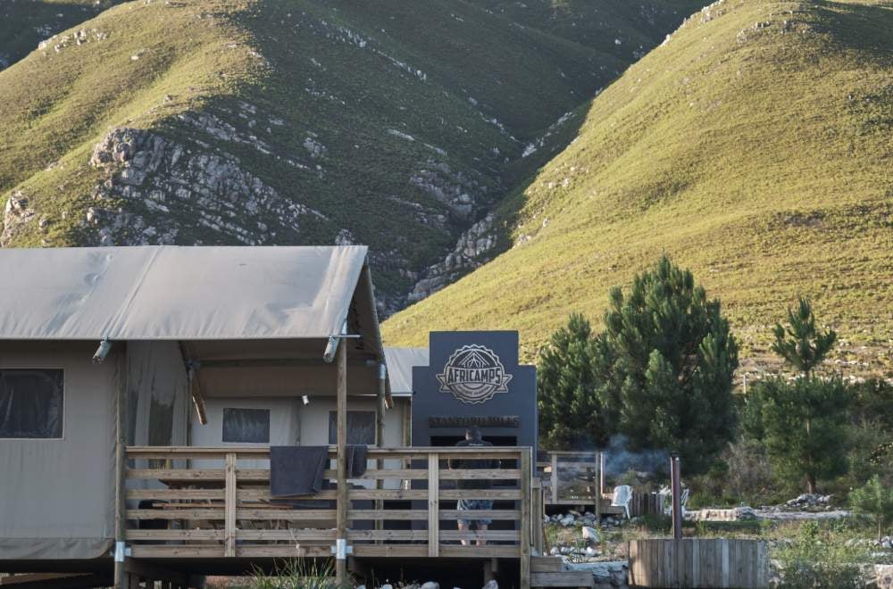 Luxurious glamping tent with expansive deck overlooking rolling vineyards and mountains at Stanford Hills Estate in South Africa