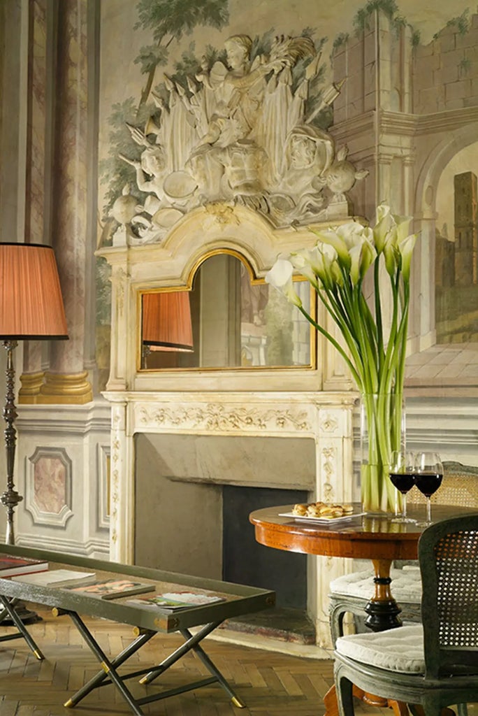 Elegant deluxe hotel room in historic Palazzo di Camugliano, featuring opulent Italian decor, antique furnishings, and soft golden afternoon light