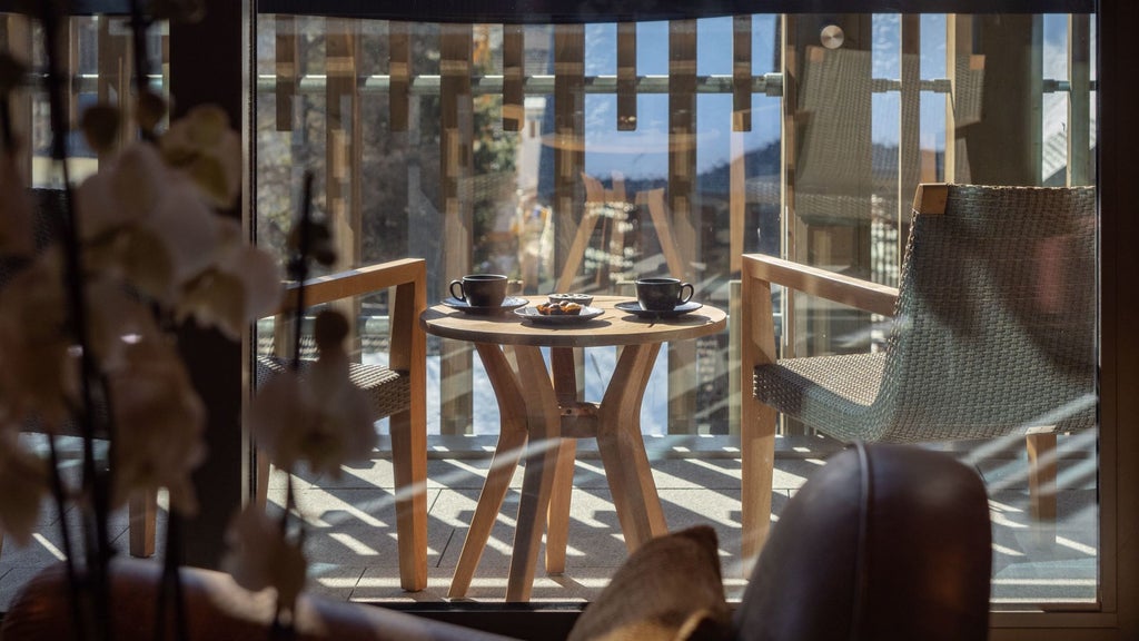 Luxurious alpine suite with minimalist Swiss design, warm wood paneling, large windows overlooking snow-capped mountain peaks at The Chedi Andermatt