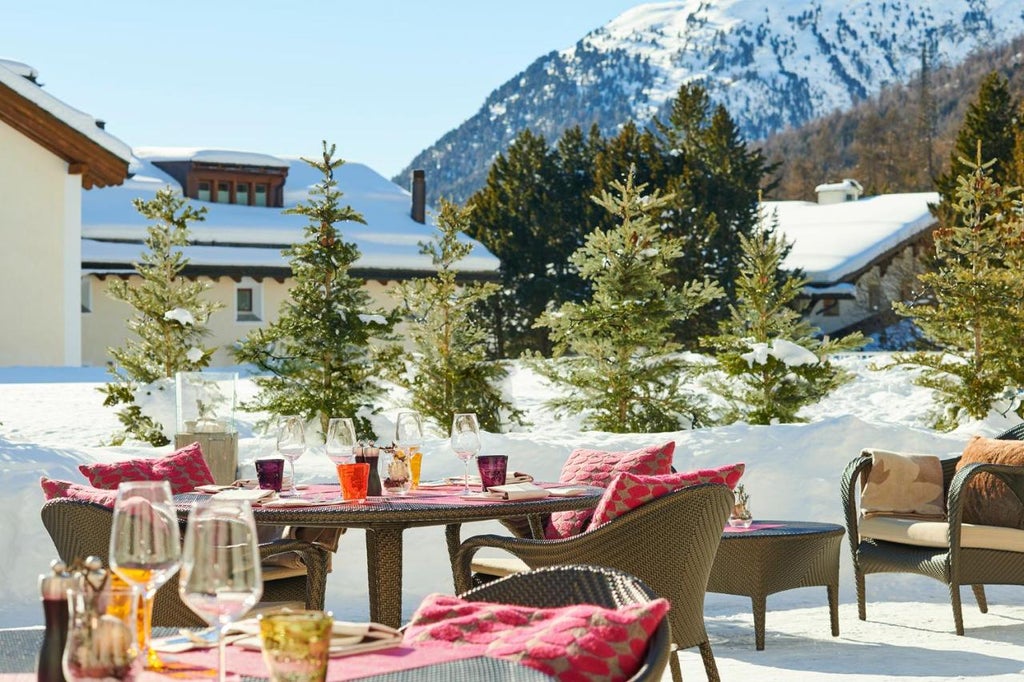 Luxurious alpine hotel with stone and wood facade nestled against snow-capped mountains, featuring elegant balconies and panoramic views