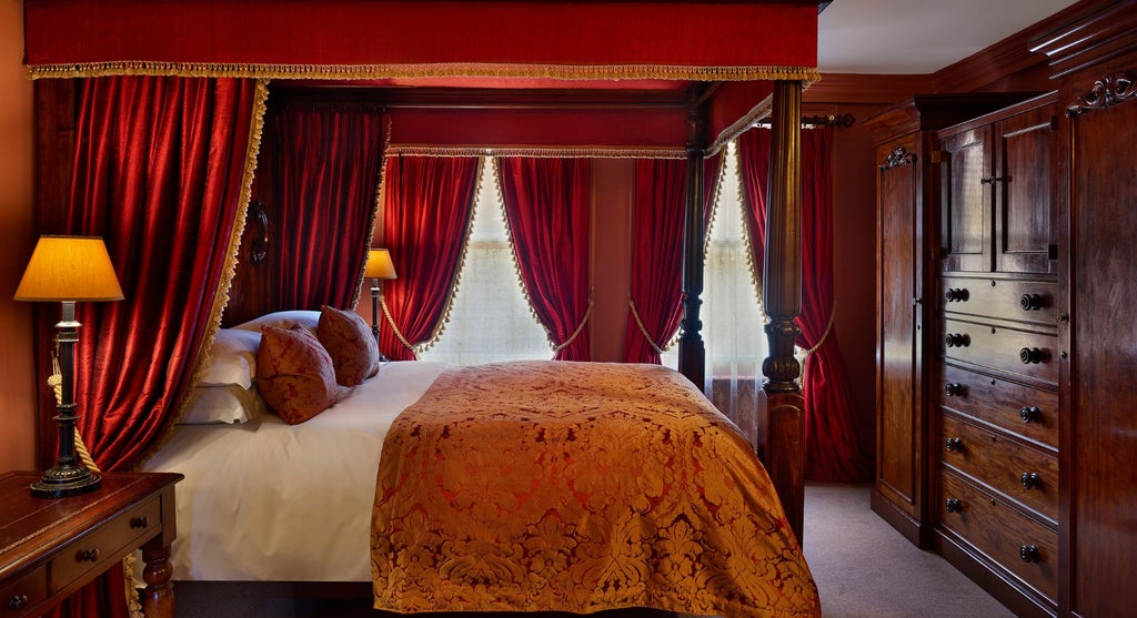 Elegant four-poster bed with rich wooden headboard in a luxurious, warmly lit superior hotel room at a historic United Kingdom accommodation